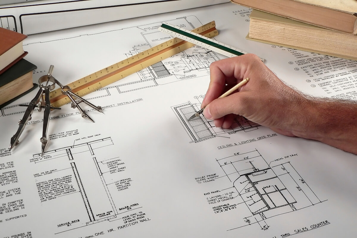 Hand Drawing Floor Plans with Compasses and Rulers on Table